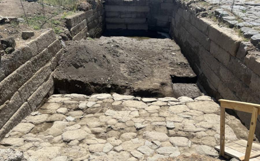 Ancient Roman water basin excavation at Gabii showing stone-lined structure carved into bedrock.