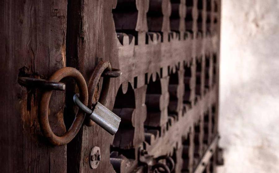 Old locked gate closed to a large castle. Source: Ekaterina / Adobe Stock