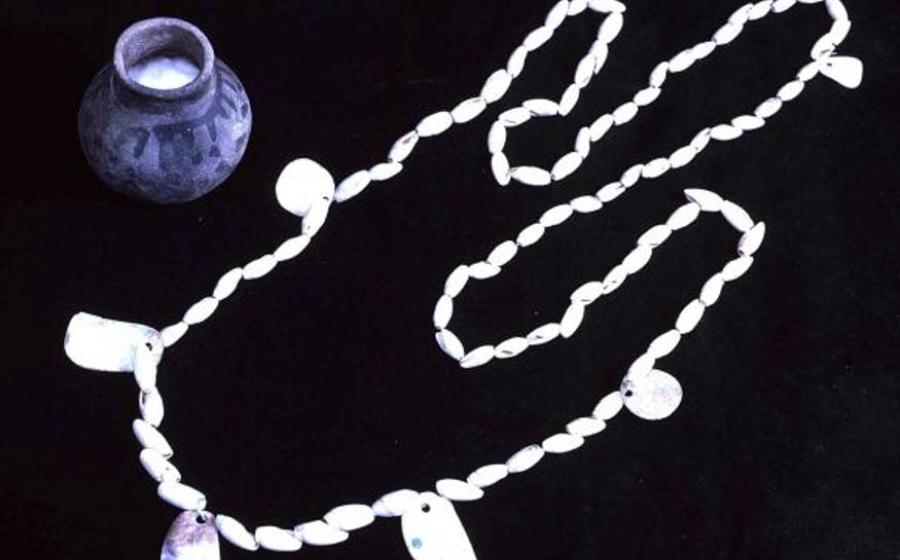 A conus shell necklace with abalone pendants and the pot in which it was found.