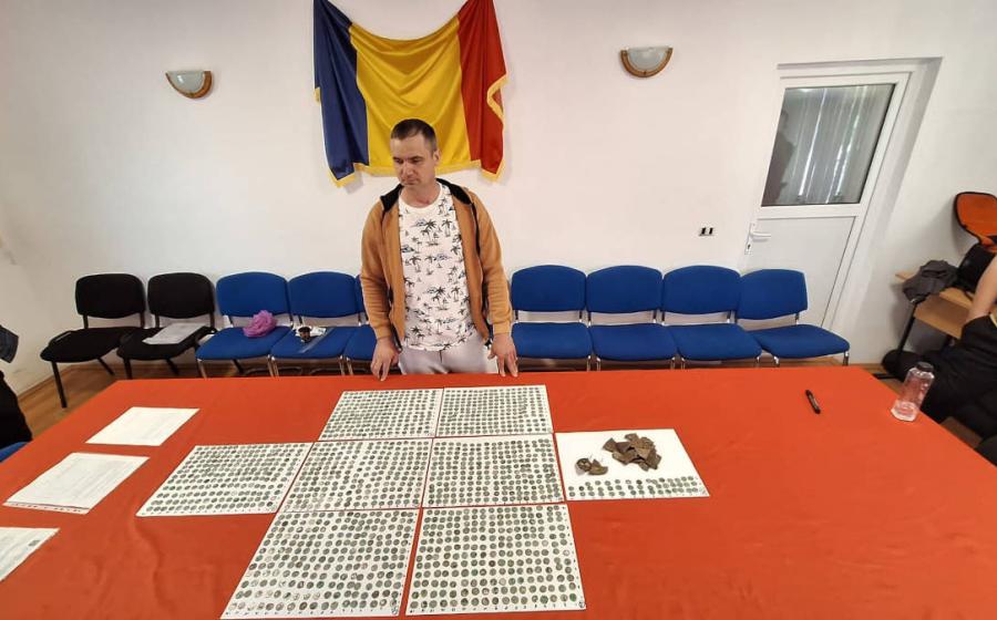 Roman metal detectorist Marius Mangeac stands in front of the Roman coins he discovered near the village of Letţa Veche.