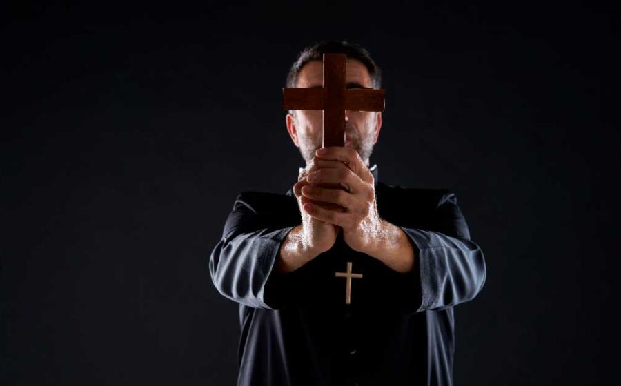 Priest conducting an exorcism. Source:  lunamarina / Adobe Stock