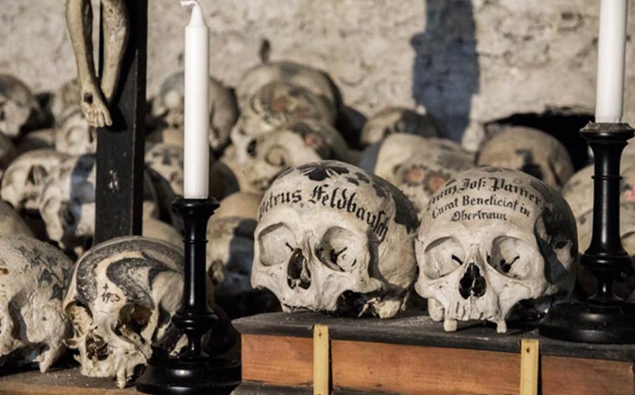 Skulls painted with names, colorful flowers, and crosses in the Charnel House in Hallstatt, Austria. Source: J. Ossorio Castillo / Adobe.