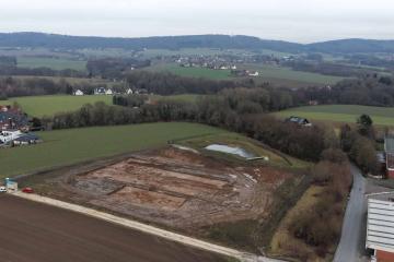 Aerial view of the excavation site for the new fire station on Lohagenweg in Hüllhorst. The line of trees marks the course of the spring stream that once provided the foundation for the original farmstead.  Photo: LWL-AfW / A. Koch