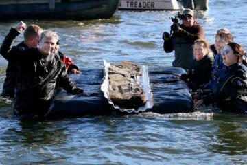 Volunteers and researhcers removing a 3,000 year old canoe from a lake.