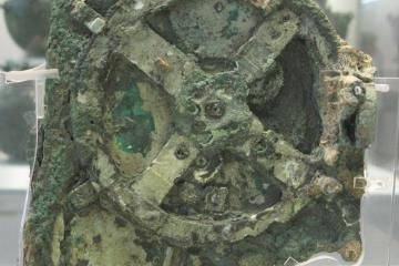 Corroded green bronze fragment with a large four-spoked gearwheel