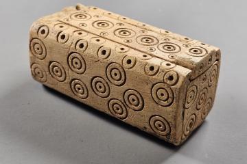 Small carved bone box with a sliding lid, decorated with rows of ring and dot circles