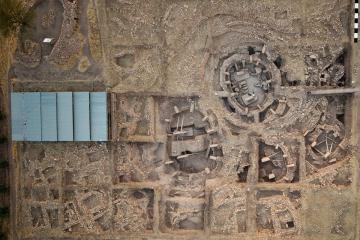 Aerial view of the main excavation area at Göbekli Tepe, with large round stone enclosures ringed by T-shaped pillars and smaller rectangular buildings beside them