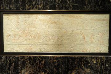 A limestone relief carved with rows of offering bearers and hieroglyphs from an Old Kingdom tomb at Saqqara
