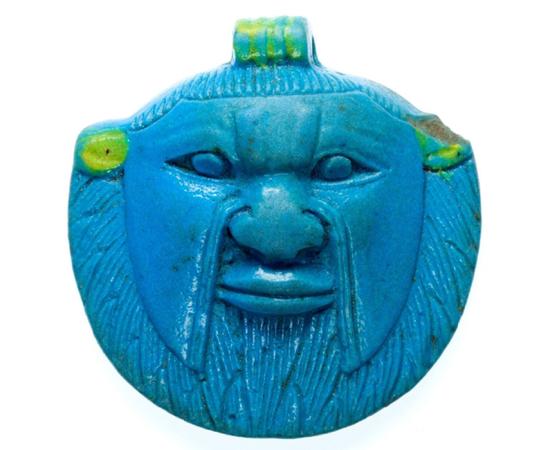 Faience amulet of the head of Bes from the Late Period, 26th to 30th Dynasties. The deity was worshipped and invoked by ordinary Egyptians as a protector against malevolent forces; design by Anand Balaji 
