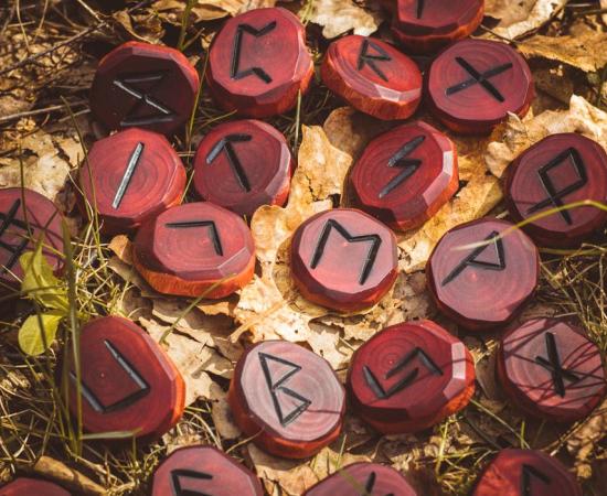 Red runes carved from wood on the ground. There are 24 runes in the Elder Futhark.