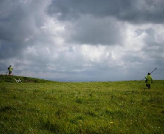 Shows Dr. Catherine Frieman in a field in Cornwall with survey equipment. Credit: ANU.