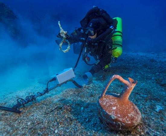 Diver Alexandros Sotiriou finds a ceramic table jug and a bronze rigging ring from the Shipwreck. 