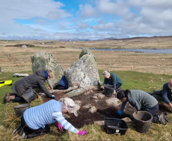 Archaeologists and community volunteers excavate around the surviving upright stones of the Leaval chambered cairn