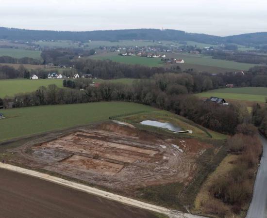 Aerial view of the excavation site for the new fire station on Lohagenweg in Hüllhorst. The line of trees marks the course of the spring stream that once provided the foundation for the original farmstead.  Photo: LWL-AfW / A. Koch