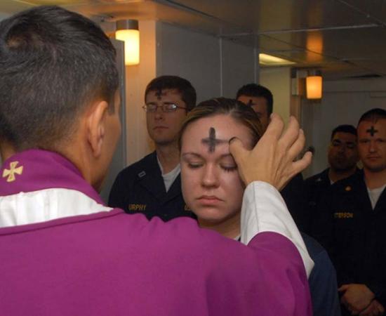US Navy employees receive the sacramental ashes during an Ash Wednesday celebration. 