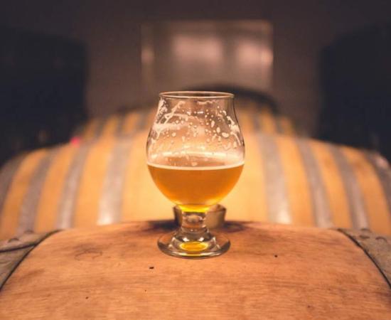 A glass of beer atop old barrels 