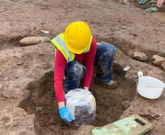 The Bronze Age burial urn about to be removed from where it was found, a tricky process!     Source: Fadó Archaeology