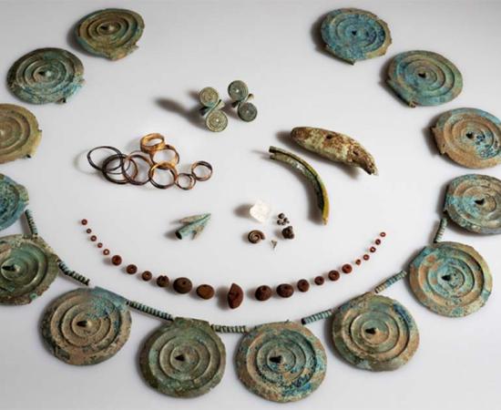 Bronze Age jewelry found in Swiss carrot field. Comprising of a necklace adorned with spiked discs, an amber necklace, finger rings, gold spirals, and distinctive discoveries like a bear tooth and an ammonite. Source: Canton of Thurgau