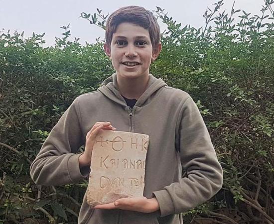 Stav Meir, holding the 1,500-year-old Byzantine inscription that he discovered near Caesarea.	Source: Karem Said/ Israel Antiquities Authority