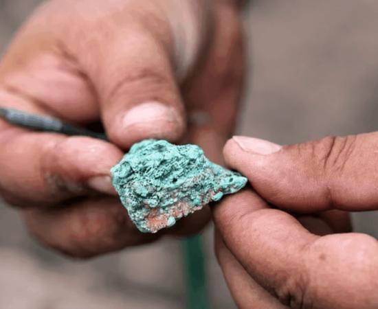 An excavator examines a malachite fragment from the 9,000-year-old Çayönü copper workshop.