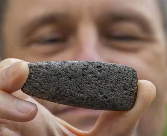 Florida Museum archaeologist Charles Cobb holds an axe head known as a celt. To create this distinct shape, a Chickasaw craftsperson reworked a Spanish iron object to mimic traditional stone versions. Credit: Florida Museum, Photo by Jeff Gage