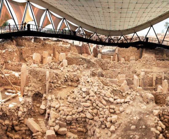 Visitors overlook the Göbekli Tepe excavation site beneath its protective roof. 