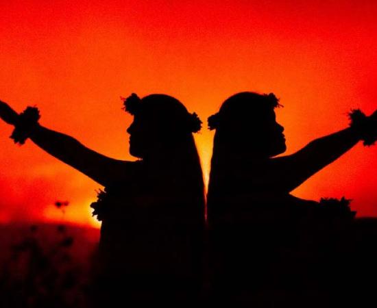 Hawaiian girls dancing in front of volcano (Julia Held/ Adobe Stock)