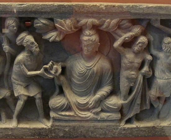 A Kushan empire (30–375 AD) frieze showing the Buddha flanked on the left by a Greek-inspired Vajrapani that clearly highlights the aesthetic nuances of Greek Buddhism.		Source: Goldsmelter / CC BY-SA 4.0