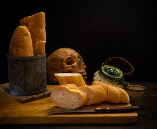 Grinding bones into bread - human skull and fresh bread.