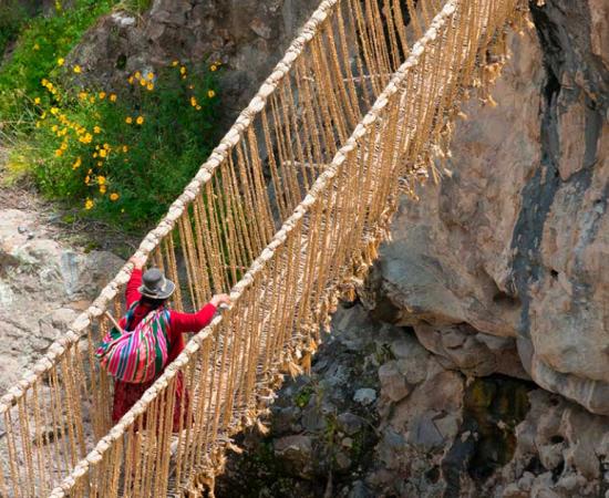 Woman crossing the Queshuachaca Inca rope bridge near Huinchiri in Peru. Source: Danita Delimont / Adobe Stock