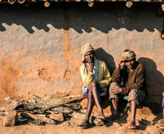 A group of Asur men outside a traditional hut in Polpol Path.