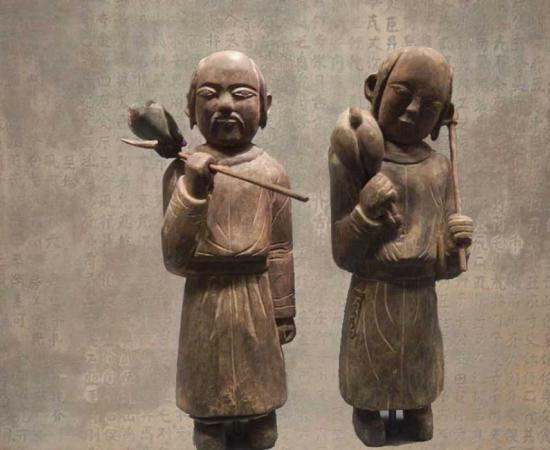 Wooden funerary figurines of Khitan people returning from a hunt. Liao dynasty (907–1125). Held at the Capital Museum, Beijing. (BabelStone/CC BY SA 3.0) Background: Stone tablet with fake epitaph inscription in the Khitan Large Script. Held at the Nationalities Museum of the Inner Mongolia University, but not on official display. It is an almost complete copy of the Epitaph for the Princess of Yongning Commandery (永寧郡公主墓誌銘) of 1092. 