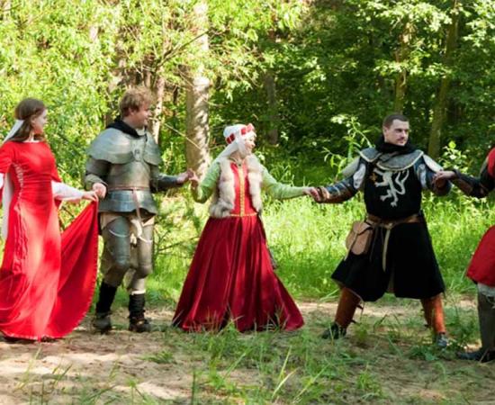 A group in traditional medieval attire engaged in a medieval circle dance.   Source: JackF /Adobe Stock                