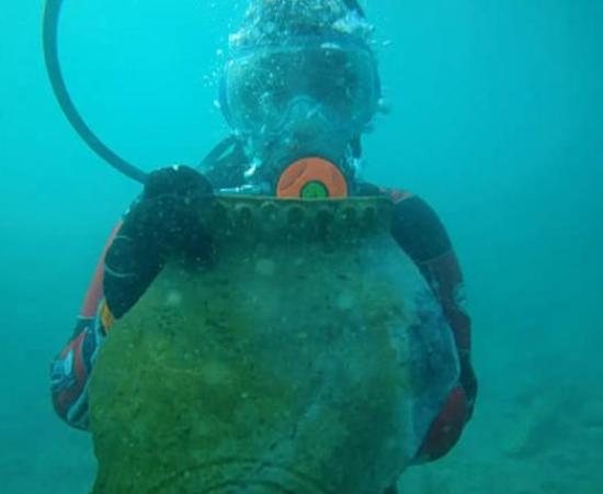 A marine archaeologist holding up an artifact under water in Lake Issyk-Kulin, Kyrgystan.