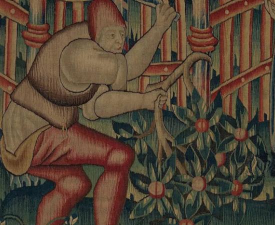 A medieval woodcutter chops down branches for firewood. 