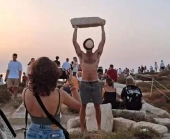 Tourist hold ancient stone aloft at Naxos, Greece.