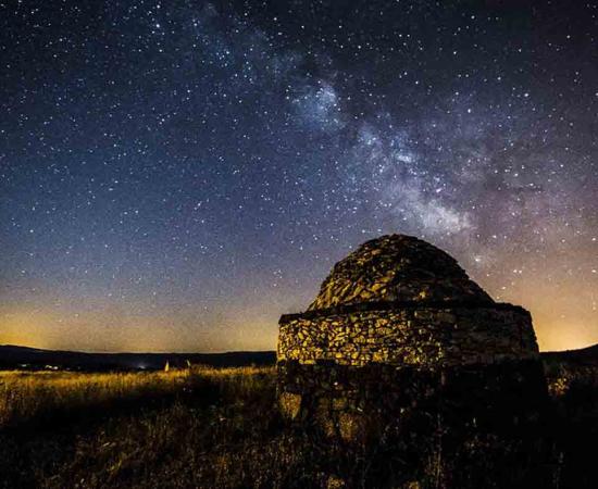 A view of a reconstructed hut at the Nuraghe Antine site at night. 