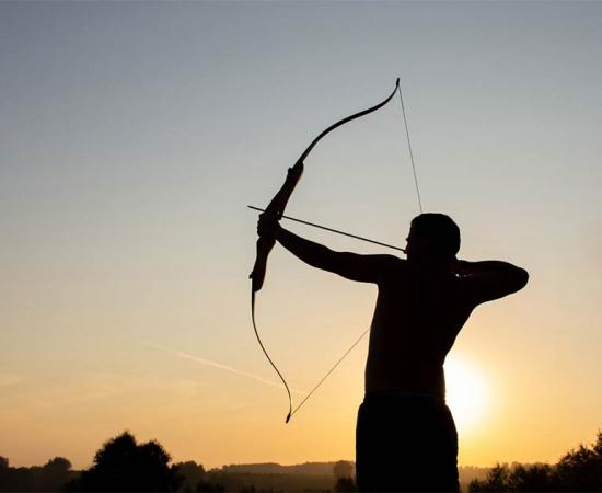 Man using bow and arrow. Credit: Oksana Volina / Adobe Stock