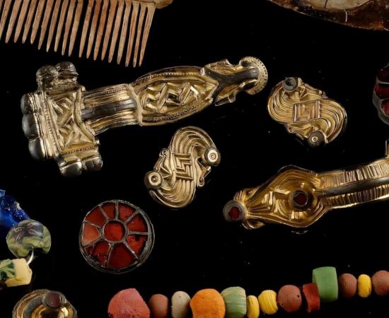 Grave items from Szeleste are the center of a shield, or umbo (upper right), various brooches (center), mosaic beads, and an antler comb (top left).
