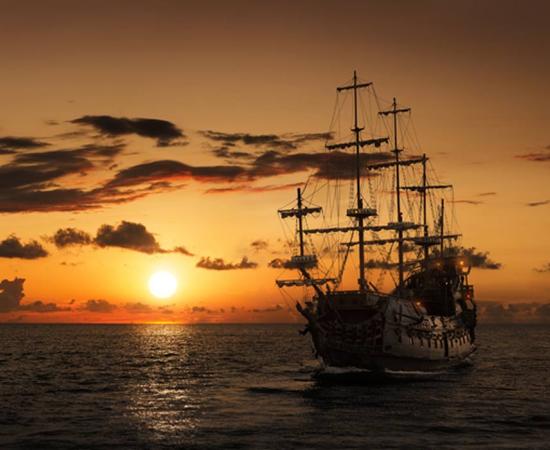 Pirate ship on the open sea at sunset. Representative image of the Queen Anne’s Revenge.