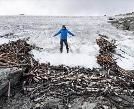 Researcher at the site of a pile of logs at the edge of the iceflow, which were used to construct the reindeer trap.