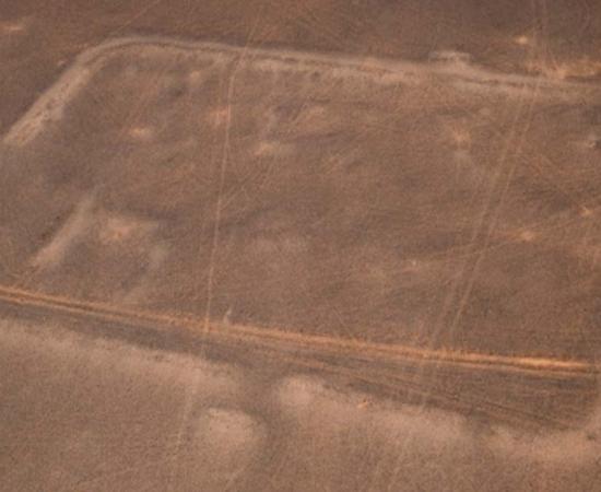 Oblique aerial view of the central camp, from the east. Possible rectilinear internal divisions are visible on the left side of the enclosure. Source: Antiquity Publications Ltd/ APAAME