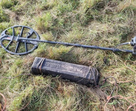 A lead ingot near the find site, with the metal detector that found it.