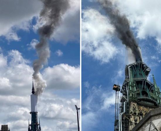 Tower of Rouen Cathedral billows smoke.