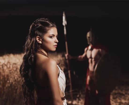 Spartan woman in foreground with her warrior husband in the background.   Source: serhiibobyk / Adobe stock