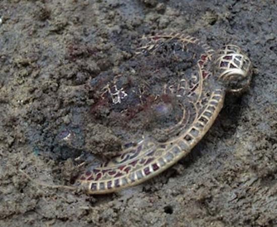 The gold pendant found in the soil. 