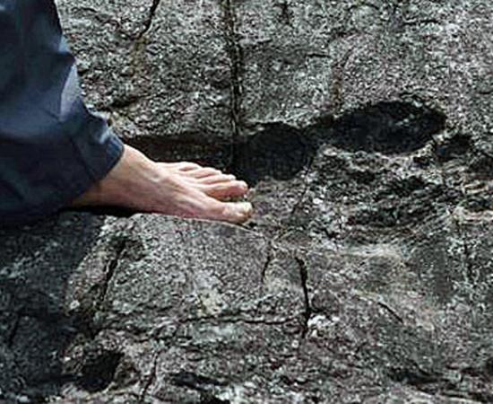 A man stands in what appears to be a giant footprint in bedrock in Pingyin China