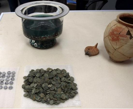 The ancient Roman coins, dating to the 1st century AD alongside the clay vessel in which they were found; the owner’s name is inscribed on the vessel. 