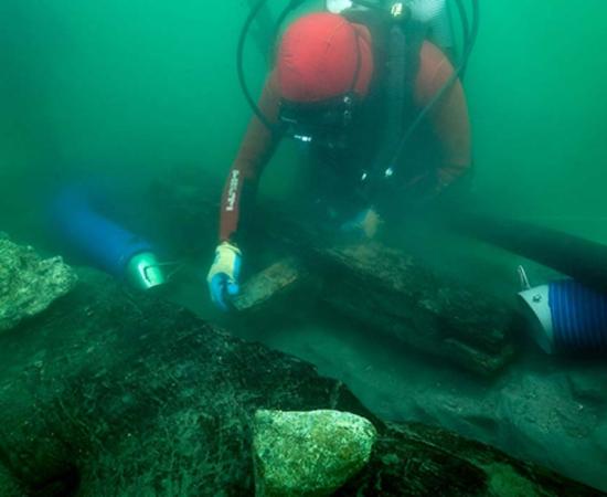 An archaeologist inspects the keel of a shipwreck discovered in the waters around the sunken port-city of Thonis-Heracleion where marine archaeologists found new Egyptian ship.
