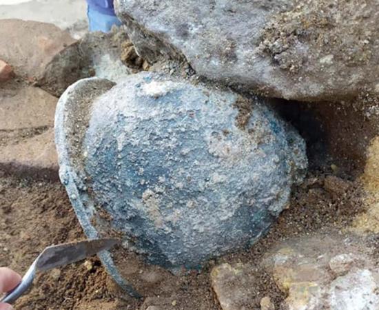 Helmet still in the ground at the Velia temple site.	Source: Parco Archeologico Paestum